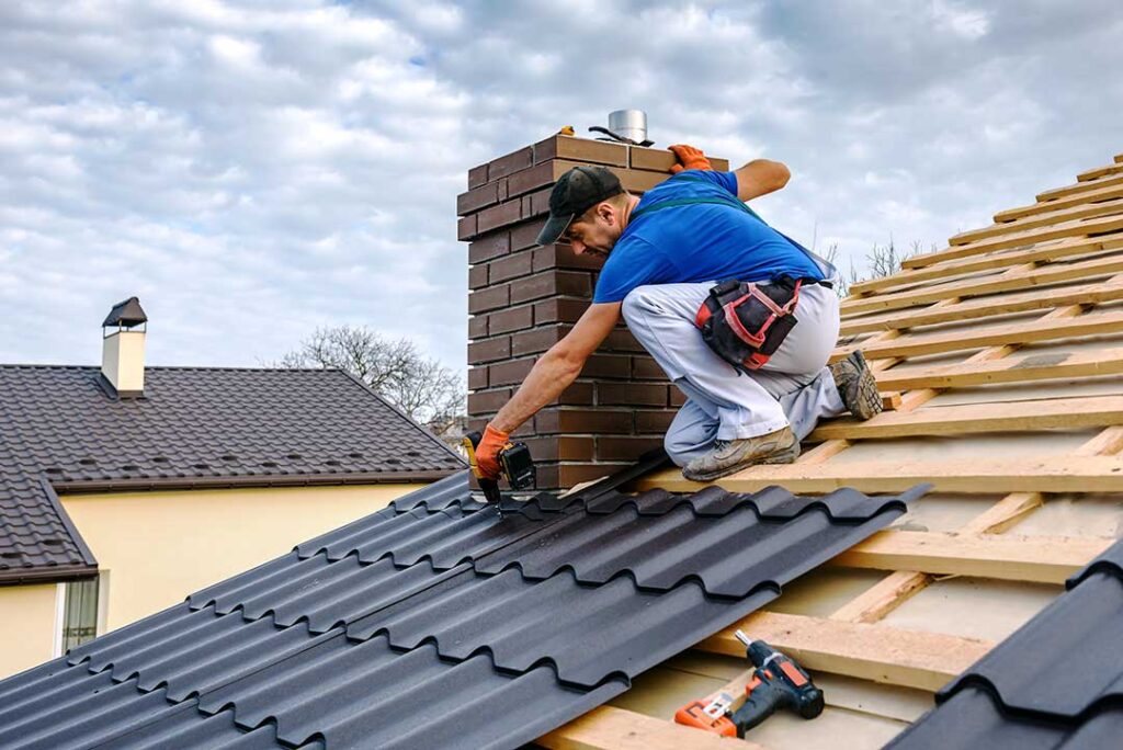 Roofing workers inspect roof decking beside stacked materials during a residential replacement.