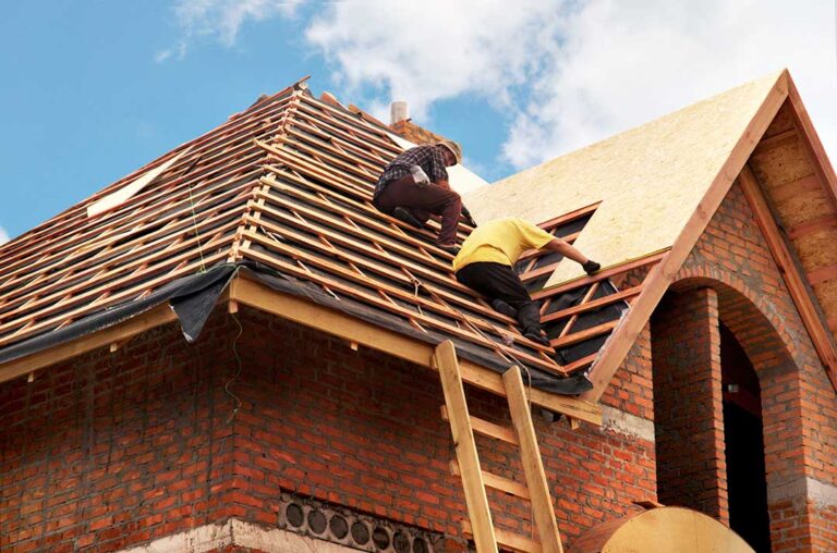 Roof valley with lifted shingles, exposed flashing, wet leaves, and water stains on the ceiling below